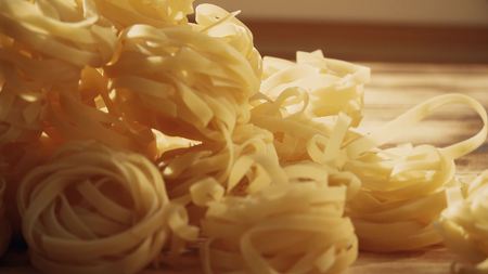 Uncooked tagliatelle, Italian pasta on a wooden table