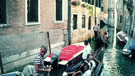 VENICE, ITALY - AUGUST 8, 2017. Famous Venetian gondolas passing between old buildingsのeditorial素材