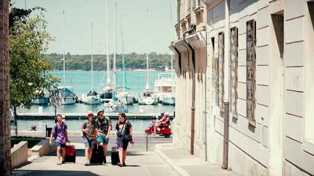 PULA, CROATIA - AUGUST 4, 2017. Young people with suitcases walk to the hotelのeditorial素材