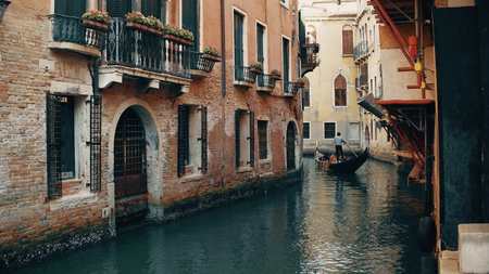 VENICE, ITALY - AUGUST 8, 2017. Venetian gondola floating between old buildingのeditorial素材