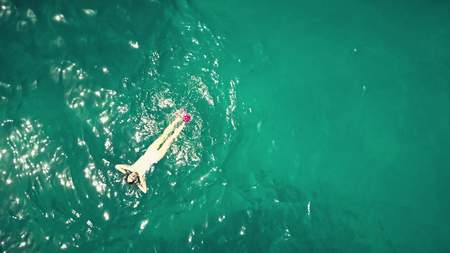 Aerial top down view of a beautiful young woman bathing in the seaの写真素材