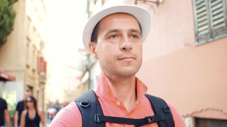 Male tourist with backpack walking down the tourist streetの写真素材