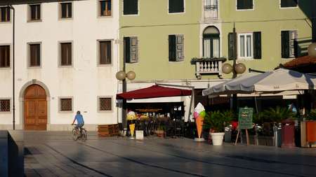 PALMANOVA, ITALY - AUGUST 11, 2017. Man riding bicycle near street cafes and old buildingsのeditorial素材