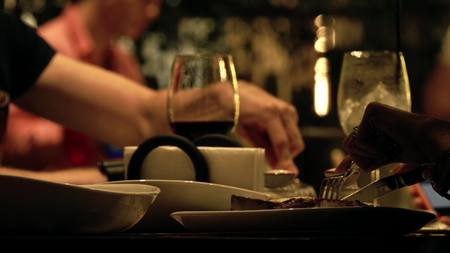 Unknown people eating steaks in a restaurant, table close-up shotの写真素材