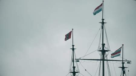 Waving flags of Netherlands and Amsterdam on the masts of an old ship memorial