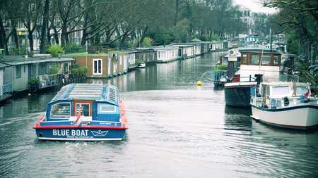 AMSTERDAM, NETHERLANDS - DECEMBER 26, 2017. River tour boat and houseboats along city canalのeditorial素材