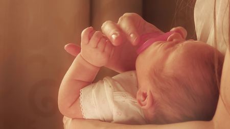 Mum soothing her fussy newborn baby with the pink pacifierの写真素材