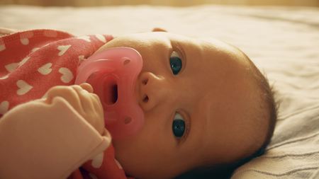 Newborn baby girl with pink pacifierの写真素材