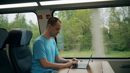 Man working on his modern laptop while travelling by train