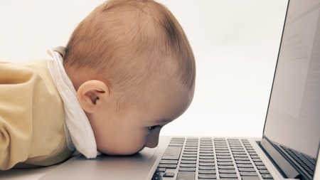 Funny baby girl trying to use a laptop in her own wayの写真素材