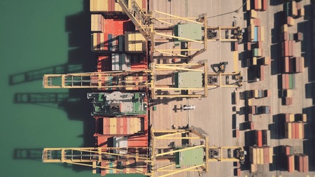 Aerial top down view of big cargo ship being unloaded at seaport container yardの写真素材