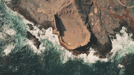 Aerial top down view of sea tide and ancient fortress ruins on the rock. Andalusia, Spain