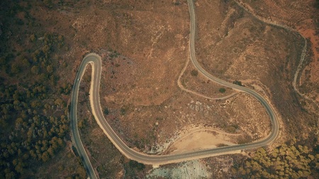 Aerial top down view of a car moving along windy road in mountainsの写真素材