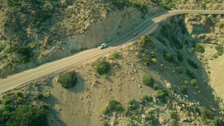 Aerial view of a Guardia Civil car moving along windy road in Andalusian mountains, Spain