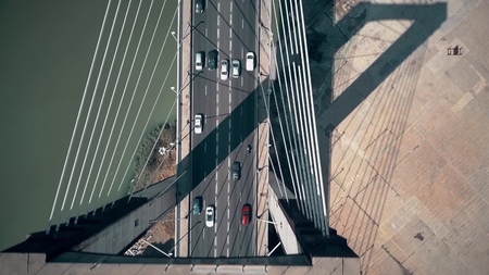 Aerial top-down view of cars moving along cable-stayed bridge
