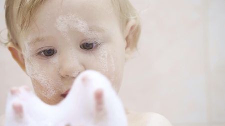 Portrait of a cute little baby playing with foam in the bathroomの写真素材