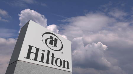 Logo of HILTON on a stand against cloudy sky, editorial 3D renderingのeditorial素材