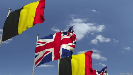 Flags of Belgium and the United Kingdom against blue sky, 3D renderingの写真素材