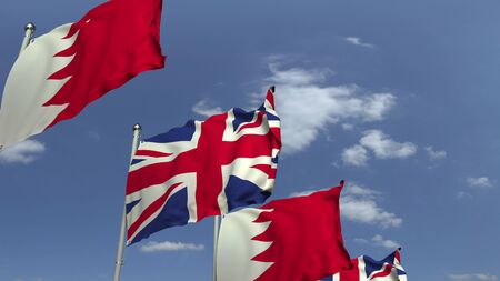 Flags of Bahrain and the United Kingdom against blue sky, 3D renderingの写真素材