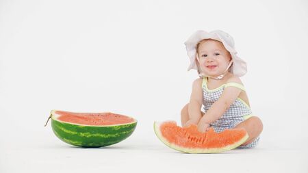 Smiling happy baby girl and sliced watermelon on white backgroundの写真素材