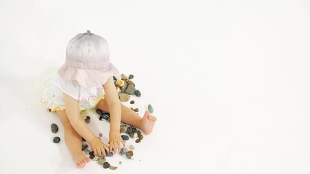 Baby girl wearing hat plays with pebble. Vacation related clip