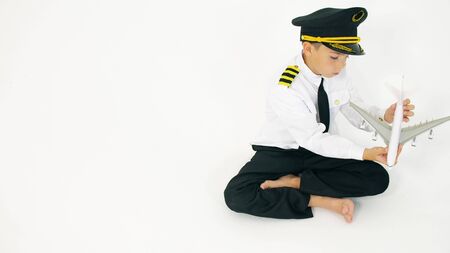 Boy wearing pilots uniform plays with toy commercial airplaneの写真素材