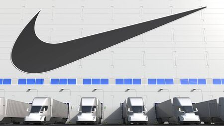 Electric semi-trailer trucks at warehouse loading bay with NIKE logo on the wall. Editorial 3D renderingのeditorial素材