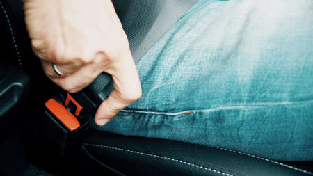 Man buckles up or fastens his seat belt. Road traffic safety related shotの写真素材