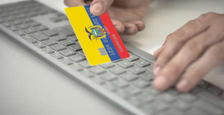 Man pays online with plastic bank card with printed flag of Ecuador. Fictional numbers