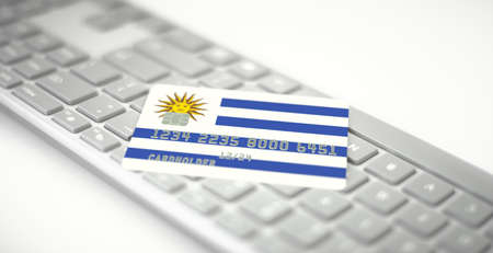 Credit card depicting flag of Uruguay on computer keyboard. Fictional numbersの写真素材
