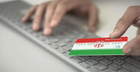 Man pays online with plastic bank card with printed flag of Iran. Fictional numbersの写真素材