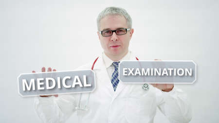Male doctor holds MEDICAL EXAMINATION text in his handsの写真素材