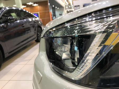 Headlight of a brand new car in the dealership, close-up shot