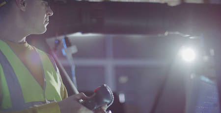 Engineer programs robot arm with industrial teach pendant control