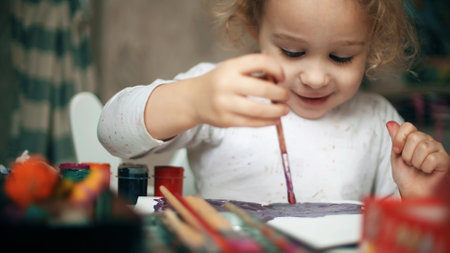 Happy blonde baby girl paints a picture at homeの写真素材