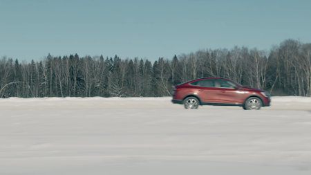 Blurred side view of unknown red car or SUV moving in rural northern area in winterの写真素材