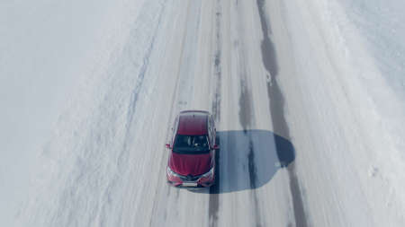 MOSCOW, RUSSIA - FEBRUARY 18, 2021. Aerial view of a red Renault Arkana SUV driving along rural snow...