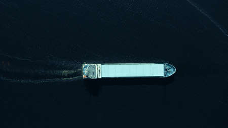 Aerial top down shot of a moving cargo ship at sea