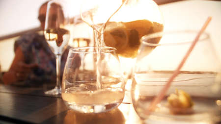 Pouring refreshing fruit drink or lemonade into glass on a hot summer day