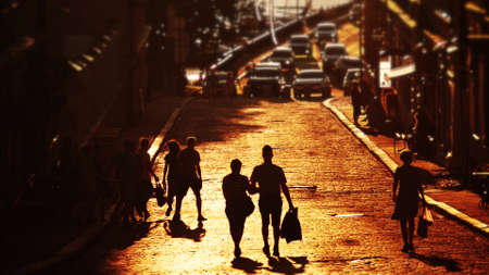 Silhouette of unknown couple walking along the street paved with cobblestone in the eveningの写真素材