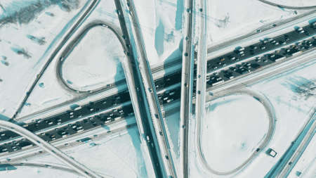 High altitude aerial top-down view of a traffic jam and highway interchange on a sunny winter day