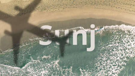 Sunj text revealed with the shadow of a flying commercial plane on the beach, aerial top-down viewの写真素材
