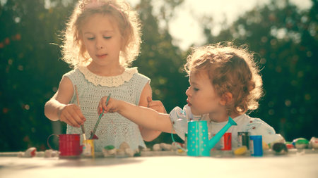 Little sisters paint with paint and brushes in the gardenの写真素材