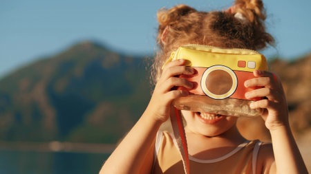 Smiling girl makes photos with a toy camera on a beachの写真素材