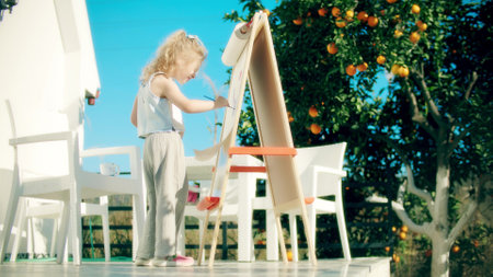 Little blonde girl paints on easel at the orange tree gardenの写真素材