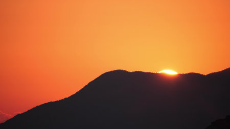 Setting sun and silhouette of the mountain. Romantic sunset tele lens shotの写真素材