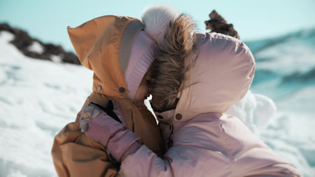Little girl kisses her baby sister in snowy mountains in winterの写真素材