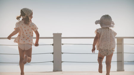 Little girls race towards sea along the jetty, slow motionの写真素材