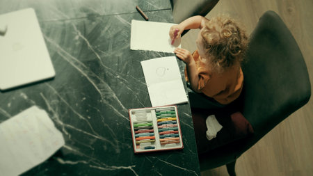 Top down view of a baby girl drawing with crayons at homeの写真素材