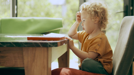 Smart little girl thinks over a new picture at homeの写真素材